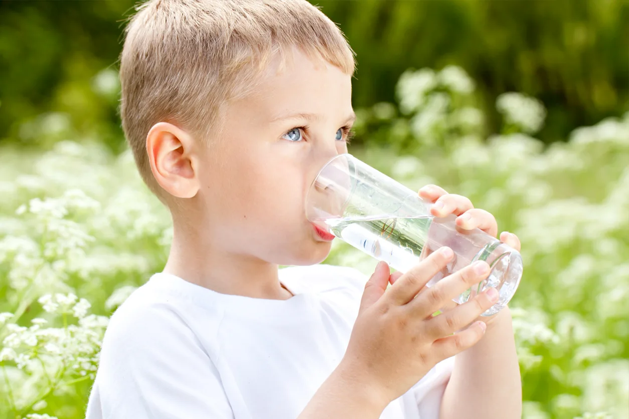 Young boy drinking water from a glass.