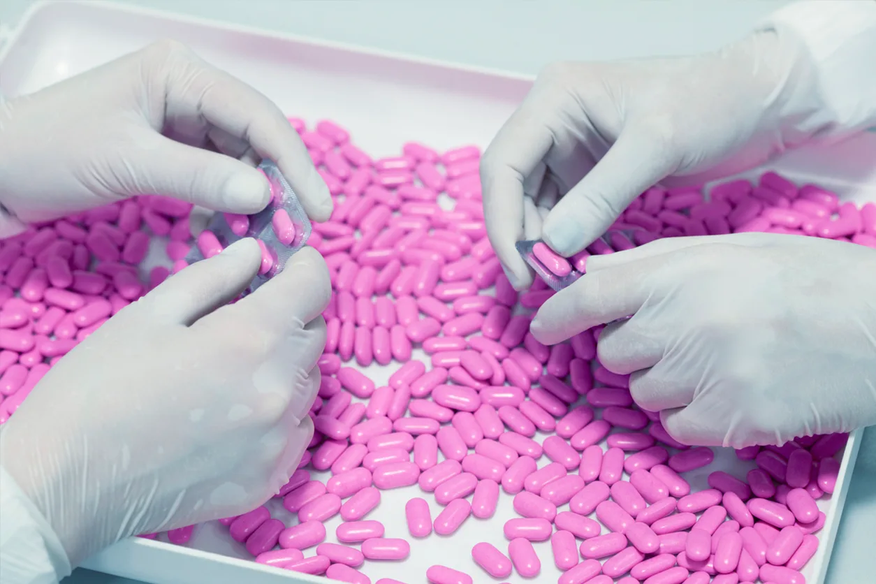 Hands sorting pink pills.