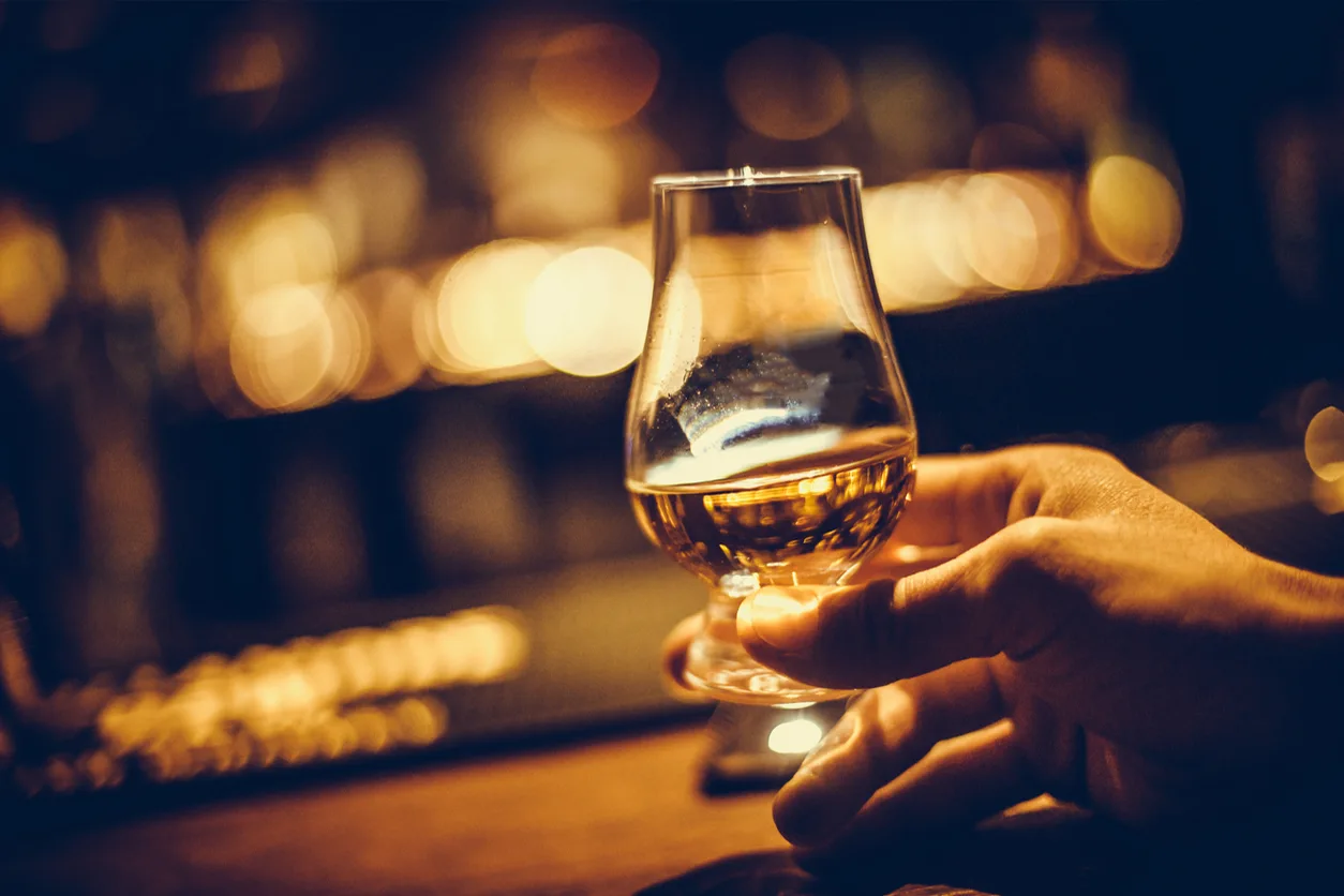 Hand holding a glass of whiskey.